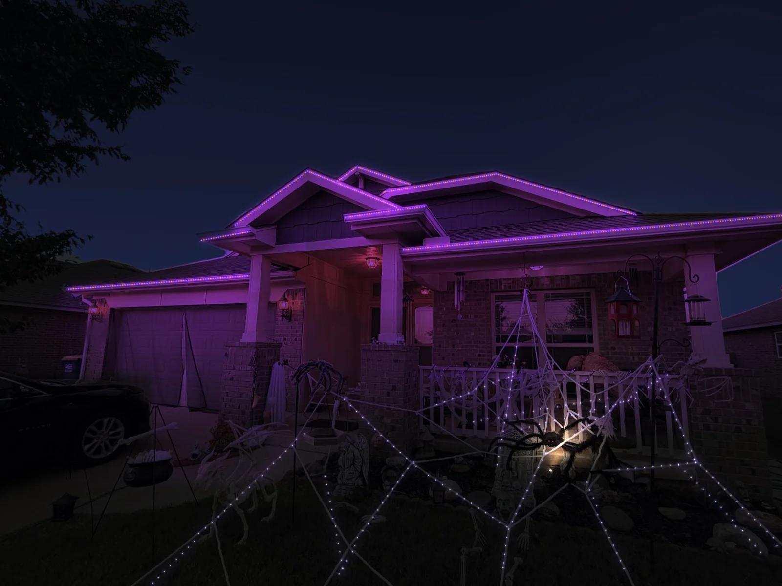 Mockup of a brick home at night with its roofline lit in purple with orange accents