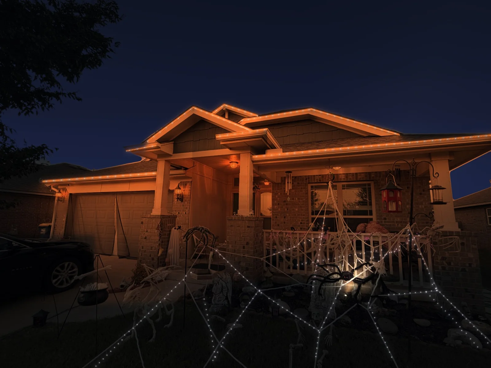 Mockup of a brick home at night with its roofline lit in orange with white accents