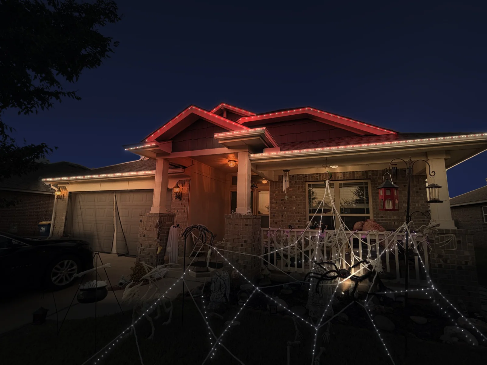 Mockup of a brick home at night with its roofline lit in crimson and cream